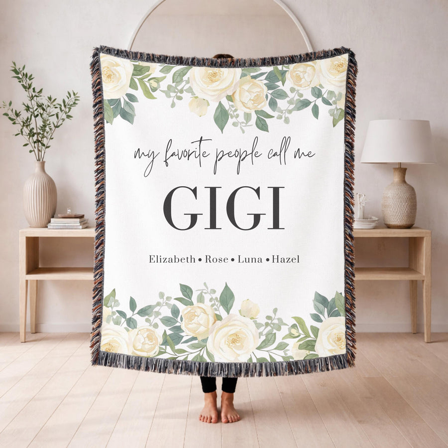 Grey fringed woven blanket printed with white roses and eucalyptus along the top and bottom, reading my favorite people call me Gigi above the names Elizabeth, Rose, Luna and Hazel.