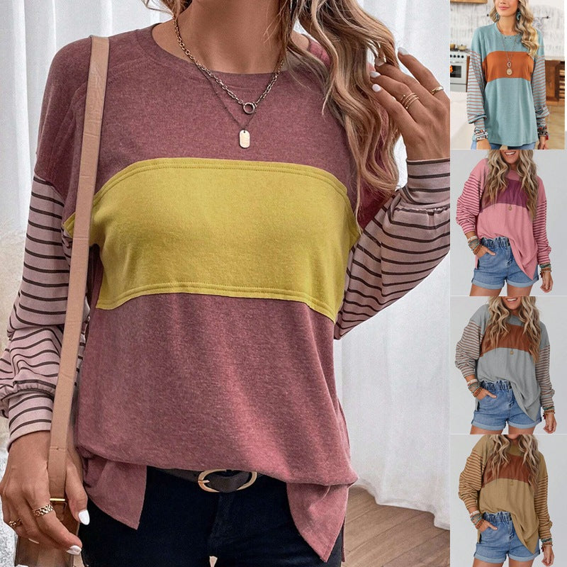 A woman wearing a loose long sleeved tee panelled in grey and rust, with fine stripes running through both sleeves and across the shoulders, cut long and straight and worn untucked.