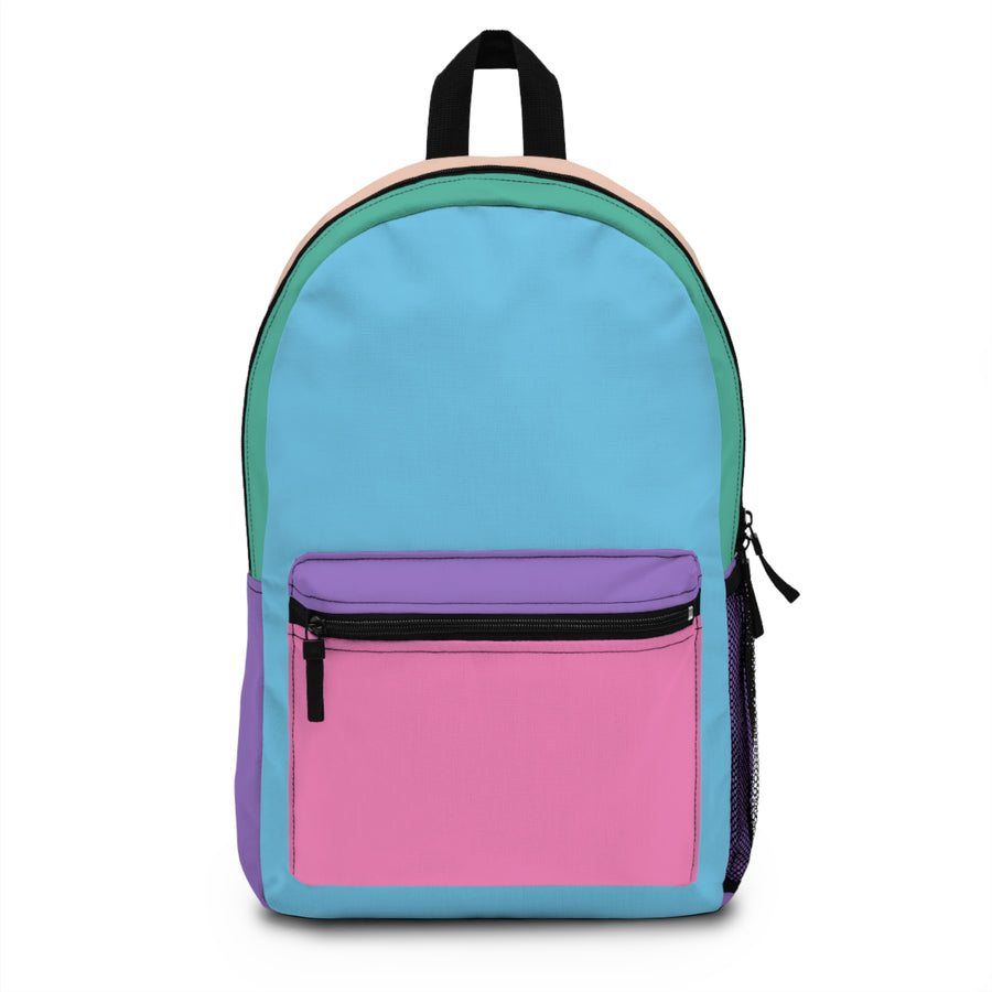 A colorblock kids backpack in blue, pink, purple, green, and peach, with a front zip pocket, mesh side pocket, and adjustable padded straps, styled on a desk with school supplies.