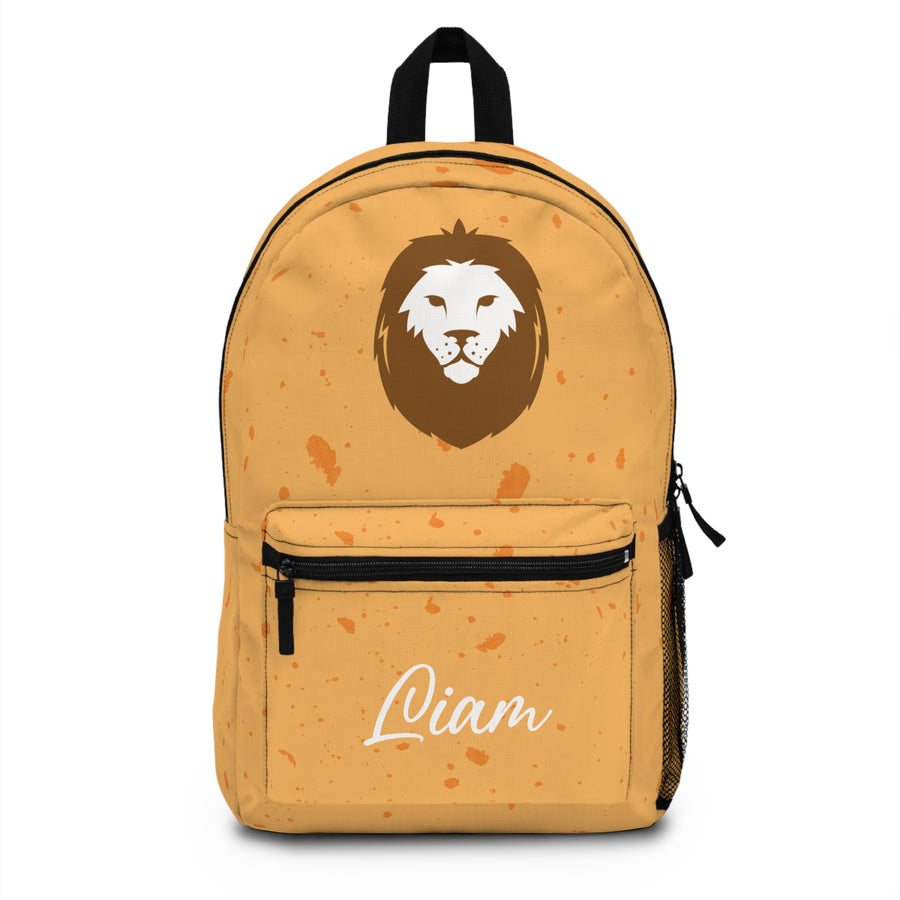 A backpack with a black top handle, front zip pocket and mesh side pocket, mustard yellow with orange speckles, a large brown and white lion face and the sample name "Liam" in white script on the pocket.