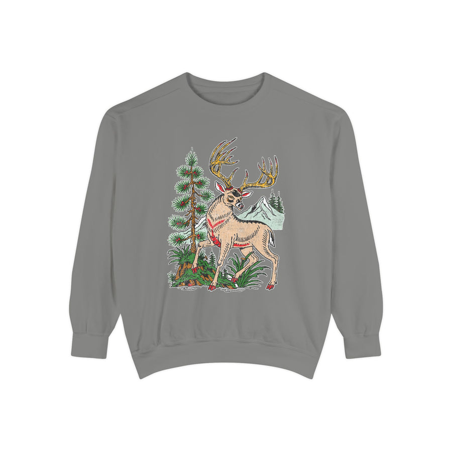 A blue crewneck sweatshirt printed with a vintage-style deer with large antlers standing beside a pine tree with mountains behind.