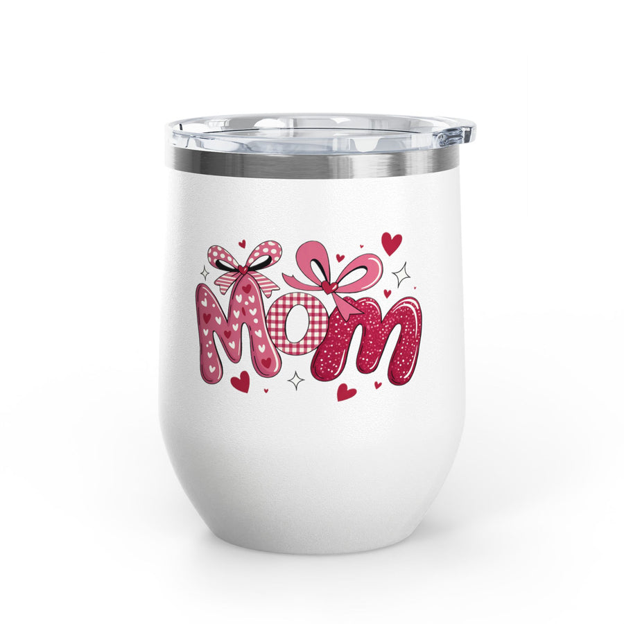 A white stainless steel stemless wine tumbler with a clear push-on lid, printed with "Mom" in pink heart-print, gingham and glitter letters topped with pink bows and small hearts.
