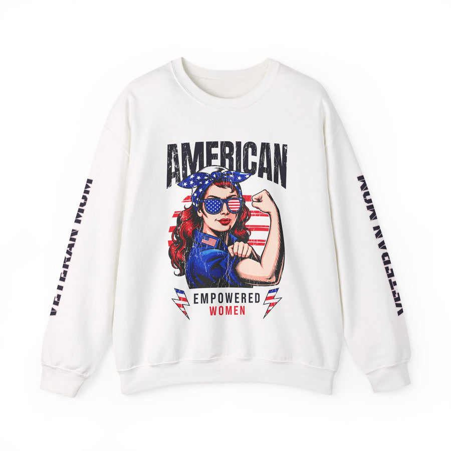 A woman wearing a white crewneck sweatshirt printed with AMERICAN above a woman flexing her arm in a flag bandana and star sunglasses, Empowered Women below, and Veteran Mom down both sleeves.