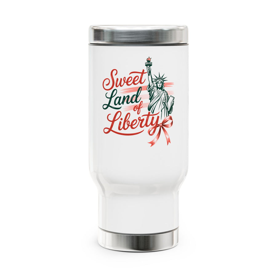 A white stainless steel travel mug with a screw-on lid, printed with a red and green "Sweet Land of Liberty" design featuring the Statue of Liberty, near a lake.