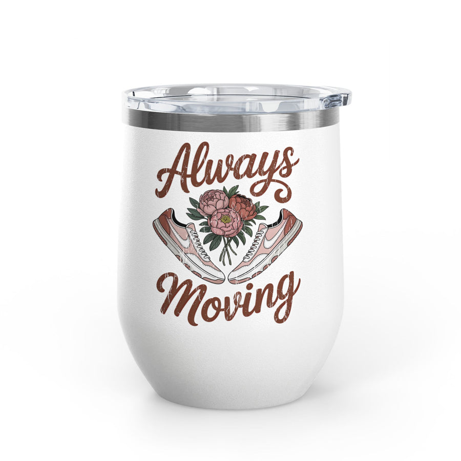 A white stainless steel stemless wine tumbler with a clear push-on lid, printed with "Always Moving" in brown script around a bouquet of pink peonies between a pair of pink and white sneakers.