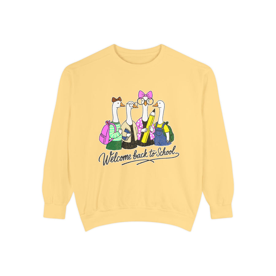 A red crewneck sweatshirt printed with four geese in backpacks, glasses and bows holding a giant pencil above Welcome back to School in script.