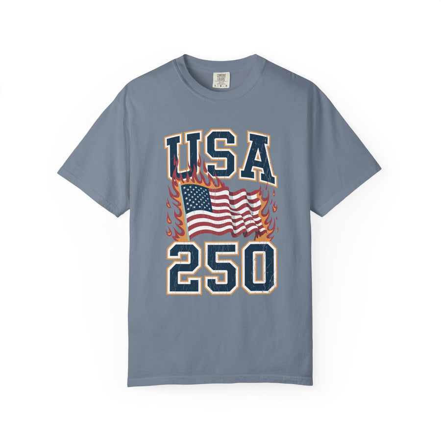 A woman wearing a blue t-shirt printed with USA 250 in varsity lettering around a waving American flag edged in flames.