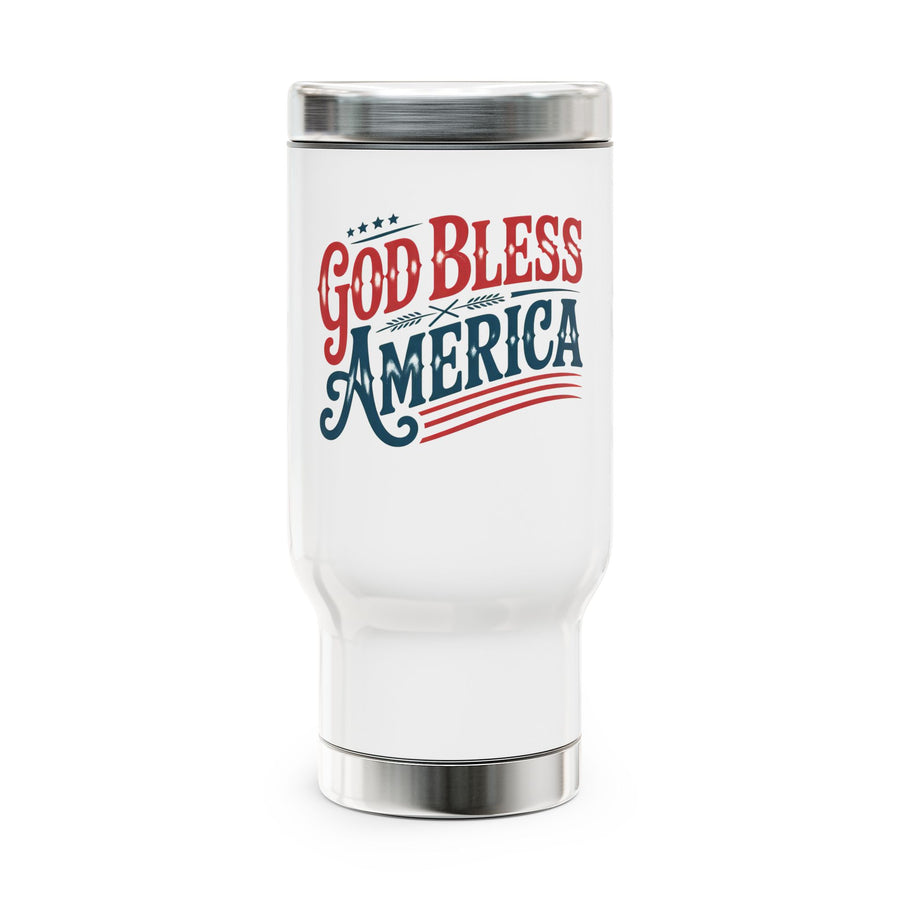 A white stainless steel travel mug with a screw-on lid, printed with a red and navy "God Bless America" design with stars and stripes, outdoors near a lake.