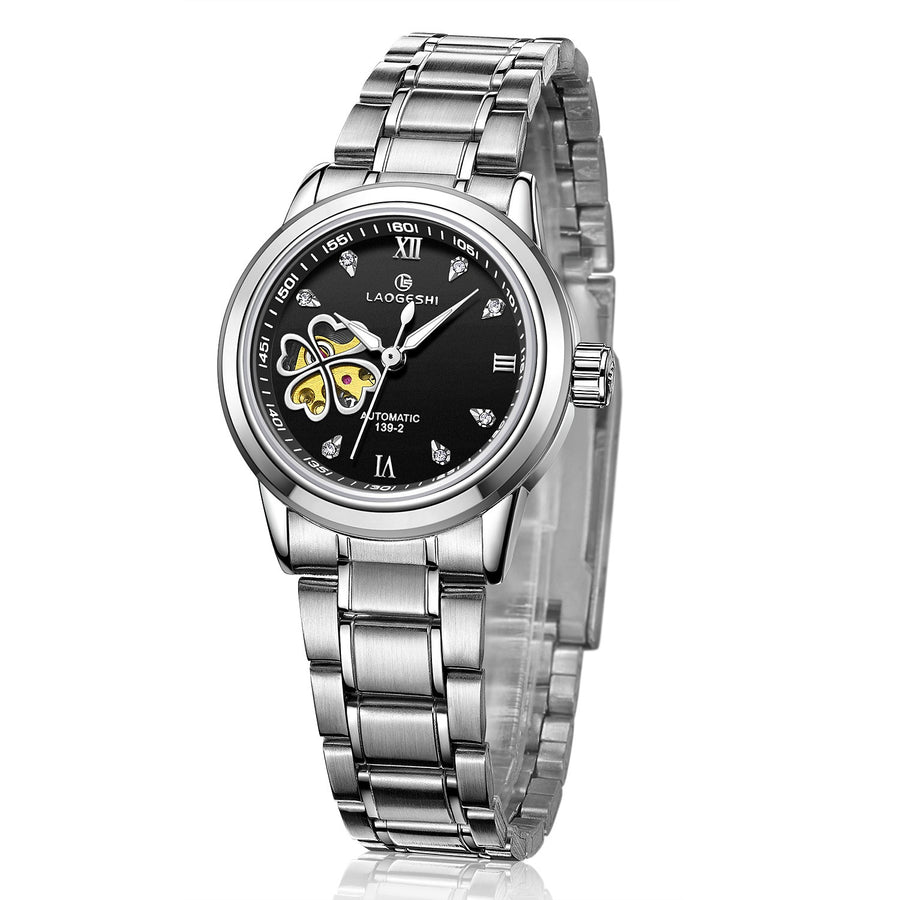 Silver automatic watch, white dial with blue four-leaf clover skeleton cutout, stainless steel bracelet, angled view