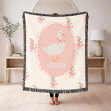 Cream fringed woven blanket with a gold lattice and pink roses and bows, centred on a scalloped pink oval holding a white goose in a pink neck bow above the name Natasha.