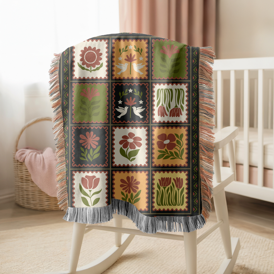 Fringed woven blanket laid out as twelve postage stamps, each holding a folk-art flower or a pair of doves in olive, ochre, cream and terracotta, inside a patterned border.