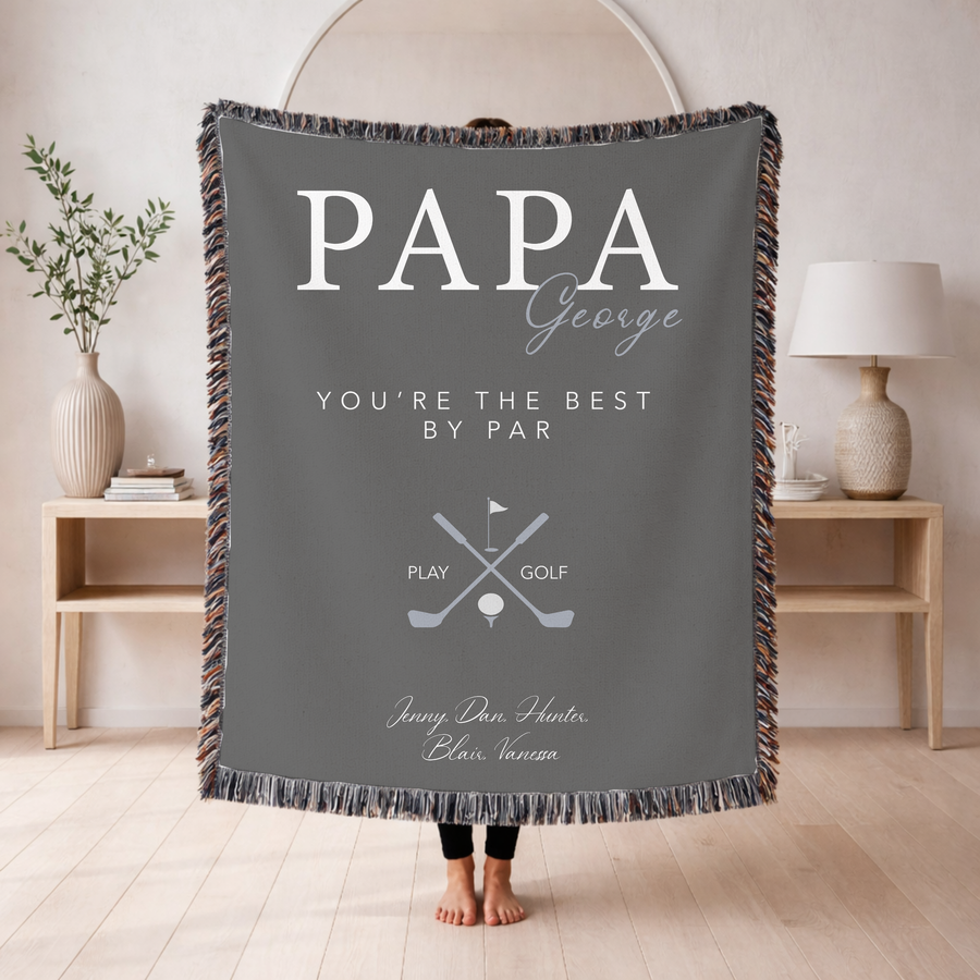 Grey fringed woven blanket reading Papa in large letters with George in script across them, above You're the Best by Par, crossed golf clubs over a ball on a tee, and five names.