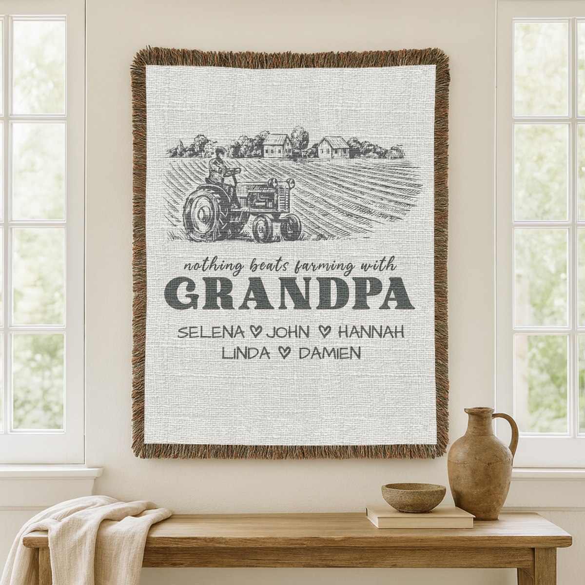 Cream fringed woven blanket with an engraved farm scene of a tractor and farmhouses, reading nothing beats farming with Grandpa above five names divided by small dark hearts.