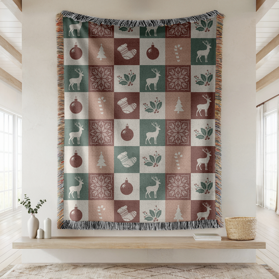 Fringed woven blanket in a checkerboard of green, rose, cream and burgundy squares, each holding a reindeer, a bauble, a stocking, a candy cane, a tree, holly or a snowflake.