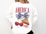 A white crewneck sweatshirt printed with AMERICA above a flag-patterned bow, two cherries and a slice of cherry pie, with 1776-2026 and 250 Years.