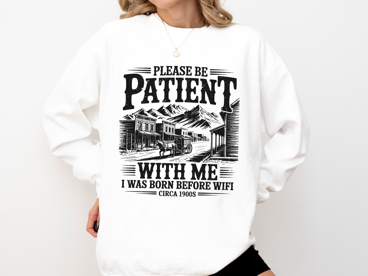 A white crewneck sweatshirt printed with an old Western town scene and the words Please be patient with me, I was born before wifi, circa 1900s.