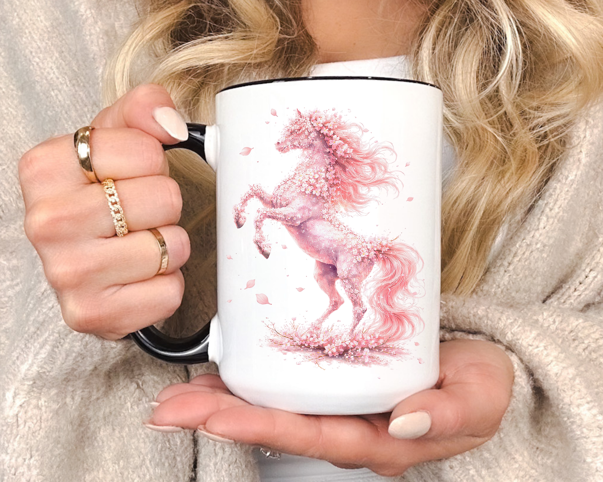 White mug with a black handle and rim, printed with a rearing horse formed entirely from pink cherry blossom, its mane and tail flowing loose and petals falling around its hooves.