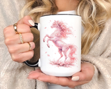 White mug with a black handle and rim, printed with a rearing horse formed entirely from pink cherry blossom, its mane and tail flowing loose and petals falling around its hooves.