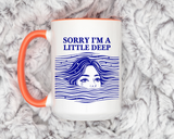 White mug with an orange handle and rim, printed in navy with the words Sorry I'm a Little Deep above a woman's face breaking the surface of stylised waves, her hair streaming out.