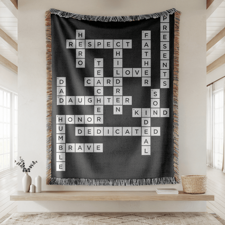 Black fringed woven blanket printed as a crossword of white letter tiles spelling out Respect, Hero, Father, Teacher, Children, Love, Daughter, Son, Kind, Honor and Brave.