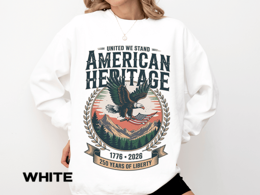 White sweatshirt printed with a bald eagle carrying a flag over mountains and pines in a laurel roundel, headed United We Stand American Heritage above 250 Years of Liberty.