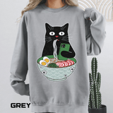 Grey sweatshirt printed with a black cat slurping noodles from a patterned ramen bowl while holding up a green phone, with egg, fish cake and spring onion in the broth below.