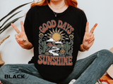 A black T-shirt printed with a retro desert scene of a sun, cacti and a winding road framed by the words Good Days Sunshine.