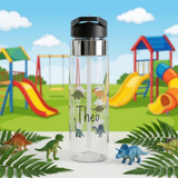 Clear plastic water bottle with a black flip lid and a straw, printed with the name Theo in black handwriting among cartoon dinosaurs, each one labelled with its own species name.