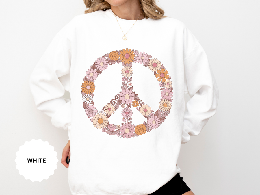 White sweatshirt printed with a large peace sign built entirely from retro daisies and blooms in dusty pink, apricot and cream, with curling leaves filling the centre of the ring.