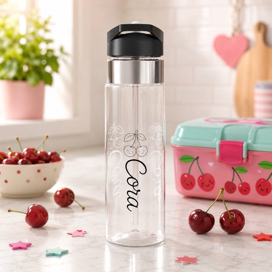 Clear plastic water bottle with a black flip lid and a straw, printed with a pair of smiling line-drawn cherries above the name Cora in black script, repeated faintly in white behind it.