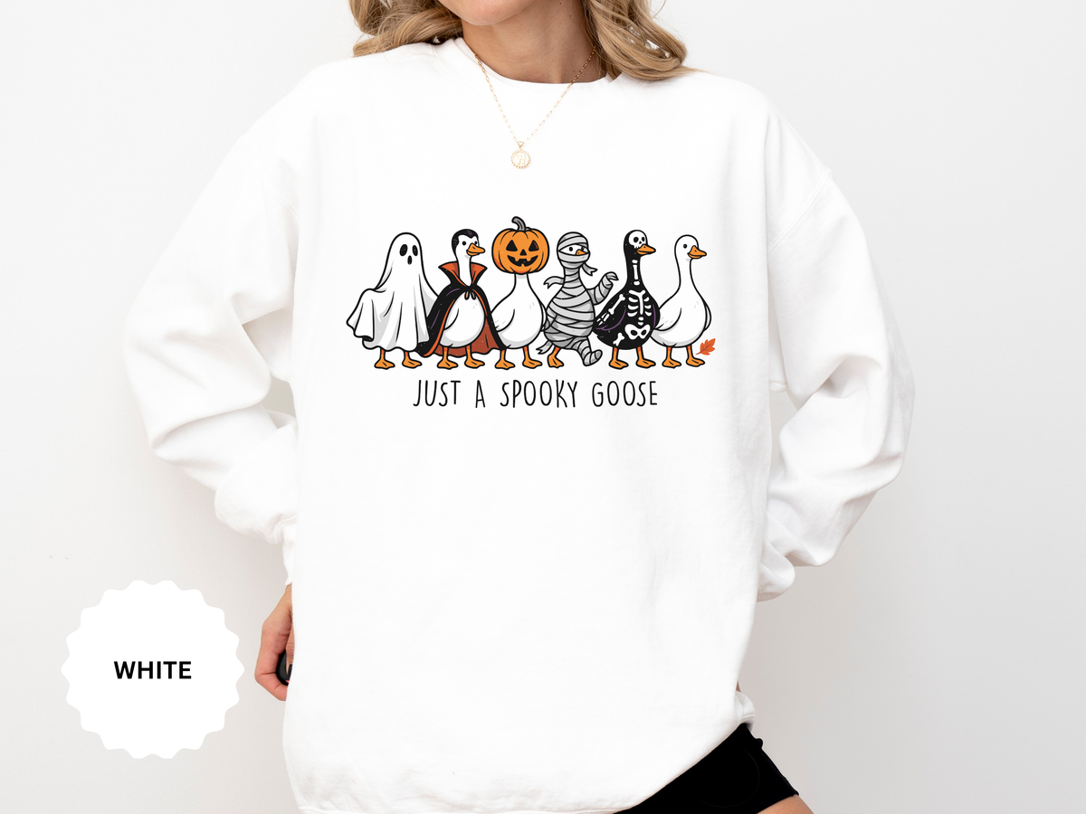 A white crewneck sweatshirt printed with a row of geese dressed as a ghost, a vampire, a pumpkin head, a mummy and a skeleton above Just a Spooky Goose.
