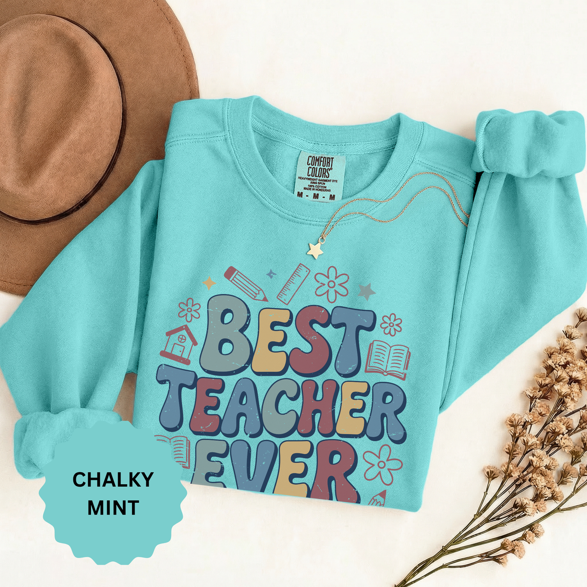 A mint crewneck sweatshirt printed with Best Teacher Ever in retro multicolored bubble letters with pencils and flowers.