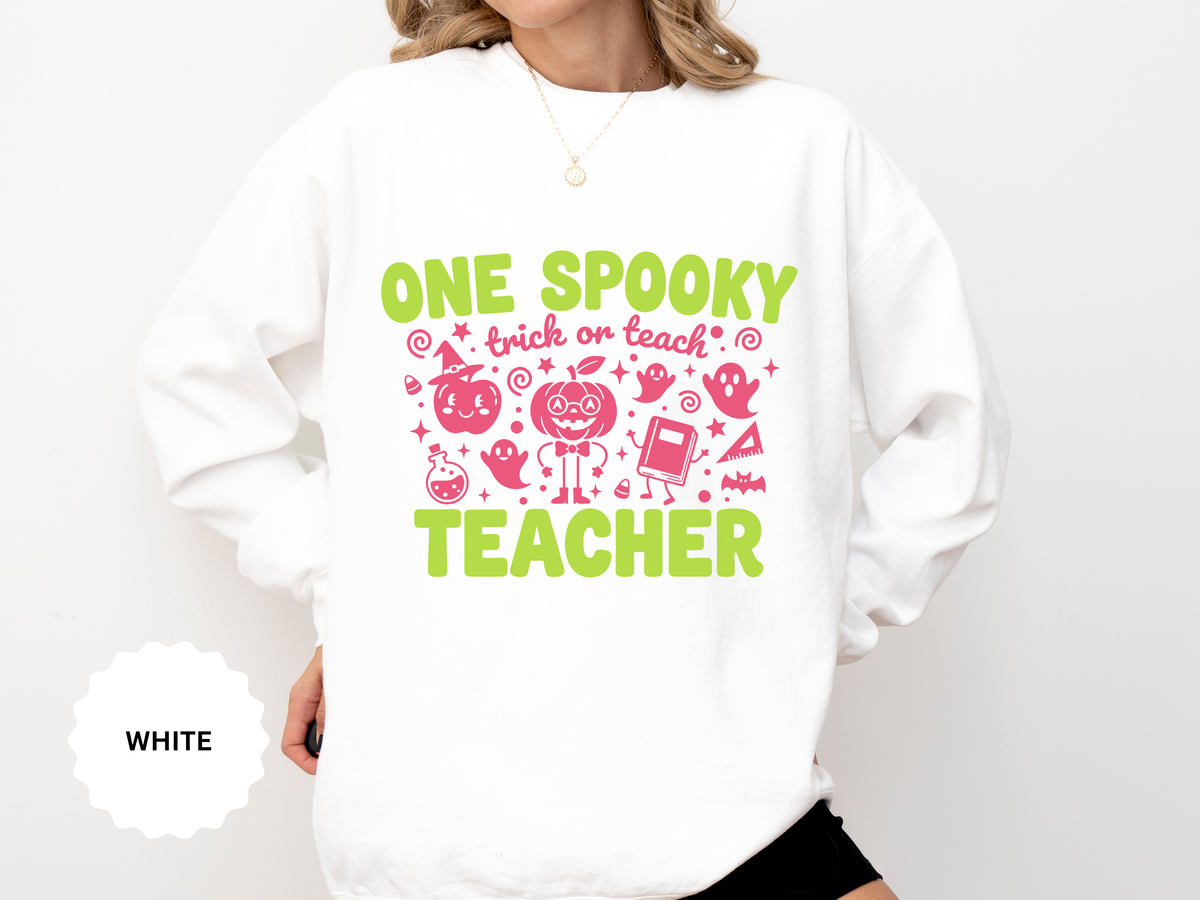 A white crewneck sweatshirt printed with One Spooky Teacher in lime green lettering with pink Halloween doodles and trick or teach.