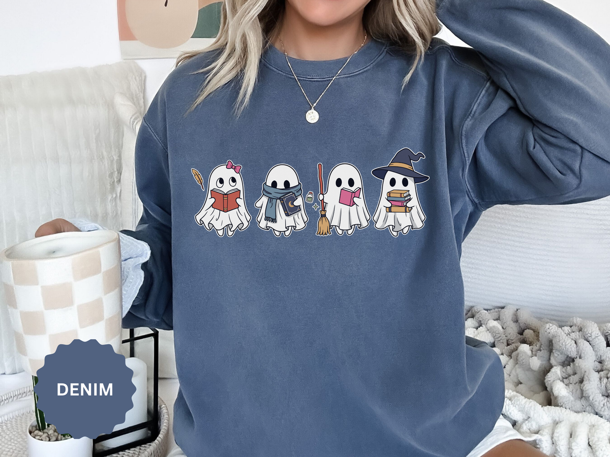 A denim-blue crewneck sweatshirt printed with four little ghosts reading books, one in a witch hat.