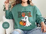 A green crewneck sweatshirt printed with a ghost carrying a crate of bottles under Just here for the Boos.