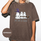 A brown T-shirt printed with three ghosts, one in a purple witch hat, sitting on a broomstick above the words We Boo at Dawn.