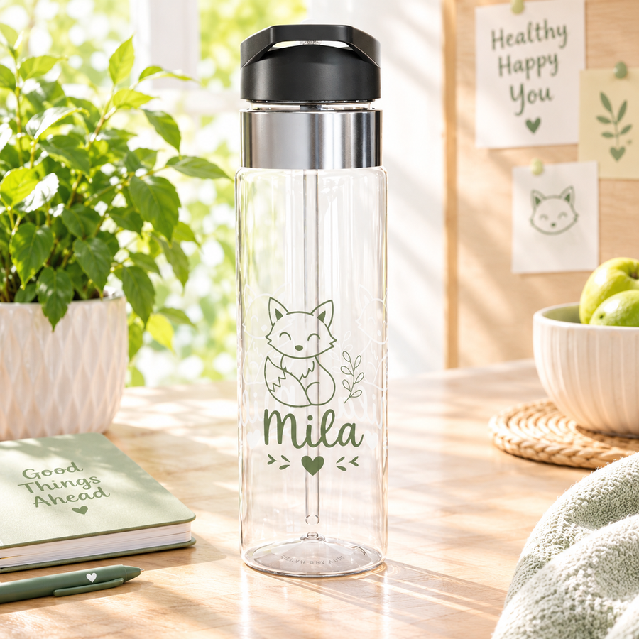 A clear Tritan water bottle with a black screw-on lid and straw, printed with woodland fox graphics and a name, styled with nature-themed decor.