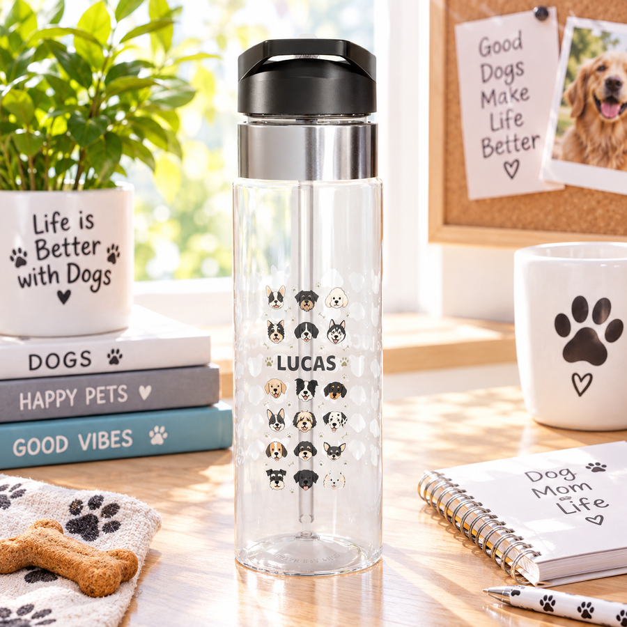 A clear Tritan water bottle with a black screw-on lid and straw, printed with colorful puppy graphics and a name, styled with kids school supplies.