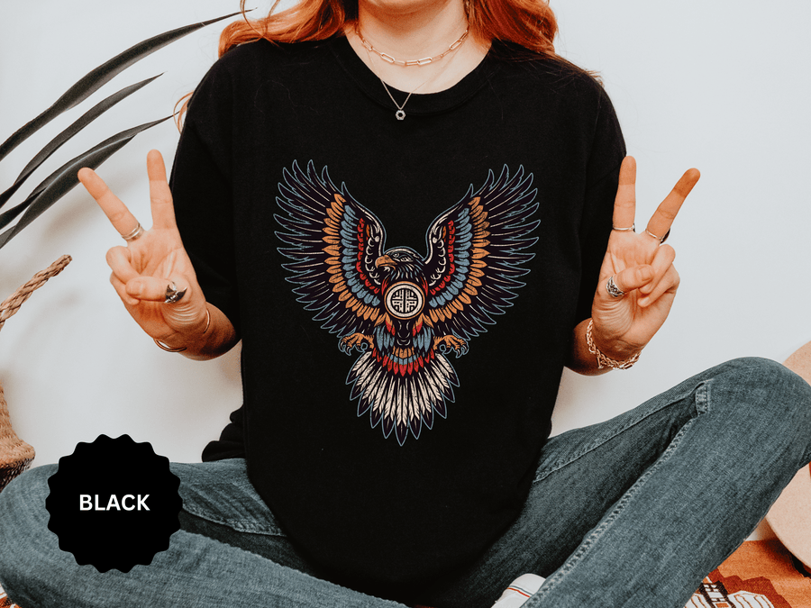 A black T-shirt printed with an ornamental eagle with spread wings in red, blue and orange patterned feathers.