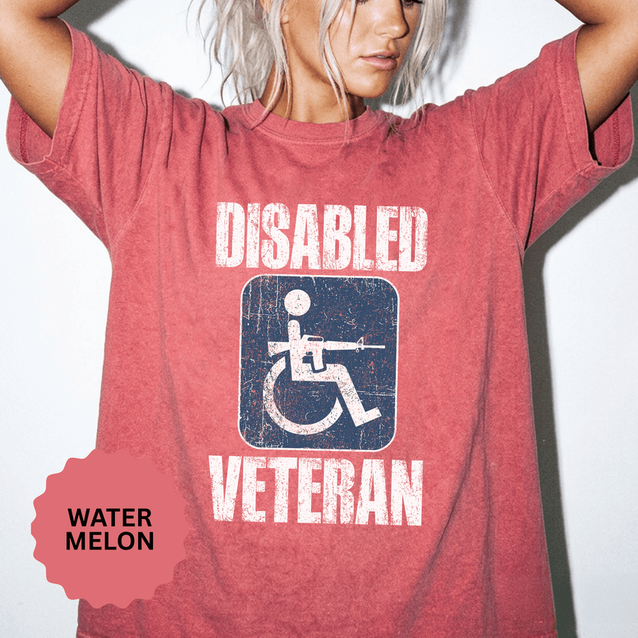 A red T-shirt printed with a distressed accessibility-symbol figure holding a rifle between Disabled and Veteran.