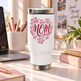 A white stainless steel travel mug with a screw-on lid, printed with a pink heart-shaped word design reading "MOM" and phrases like "my greatest love", on a desk.