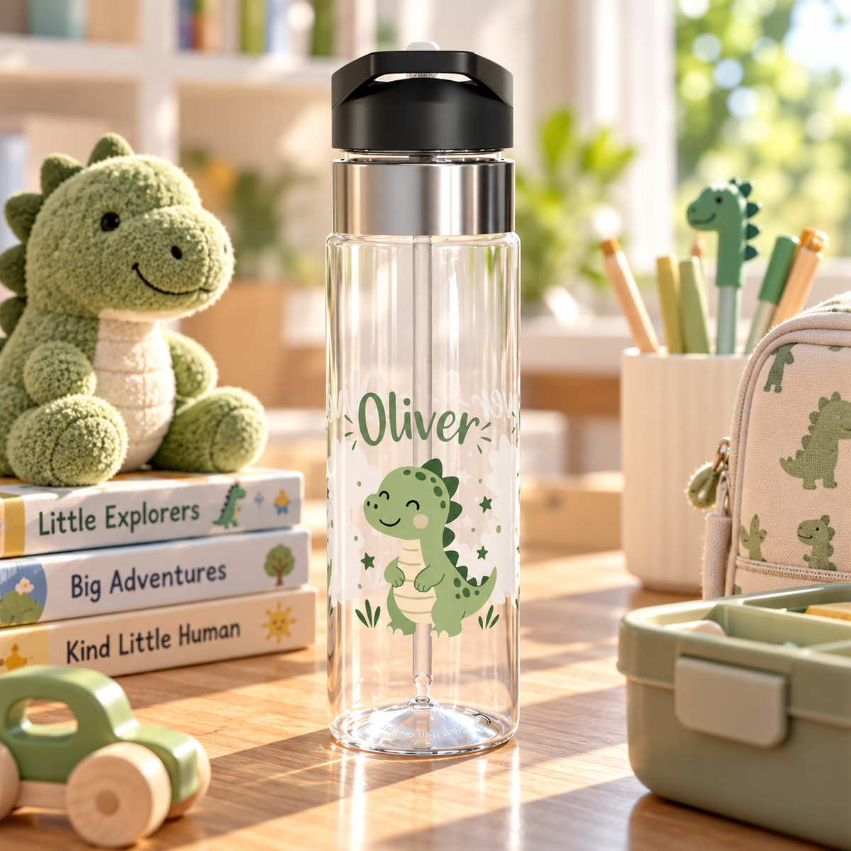 A clear water bottle with a black flip-top lid, stainless band and straw, printed with the sample name "Oliver" in green above a smiling green cartoon dinosaur with small stars.