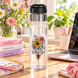 A clear water bottle with a black flip-top lid, stainless band and straw, printed with a bouquet of sunflowers, daisies and pink flowers tied with a red bow above the sample name "Avery" in script.