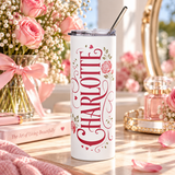 A white stainless steel skinny tumbler with a clear lid and metal straw, printed with the sample name "CHARLOTTE" in red script lettering with pink roses, small hearts and flourishes.