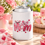 A white can cooler on a drink can, printed with "Mom" in pink heart-print, gingham and glitter letters topped with pink bows and small hearts.