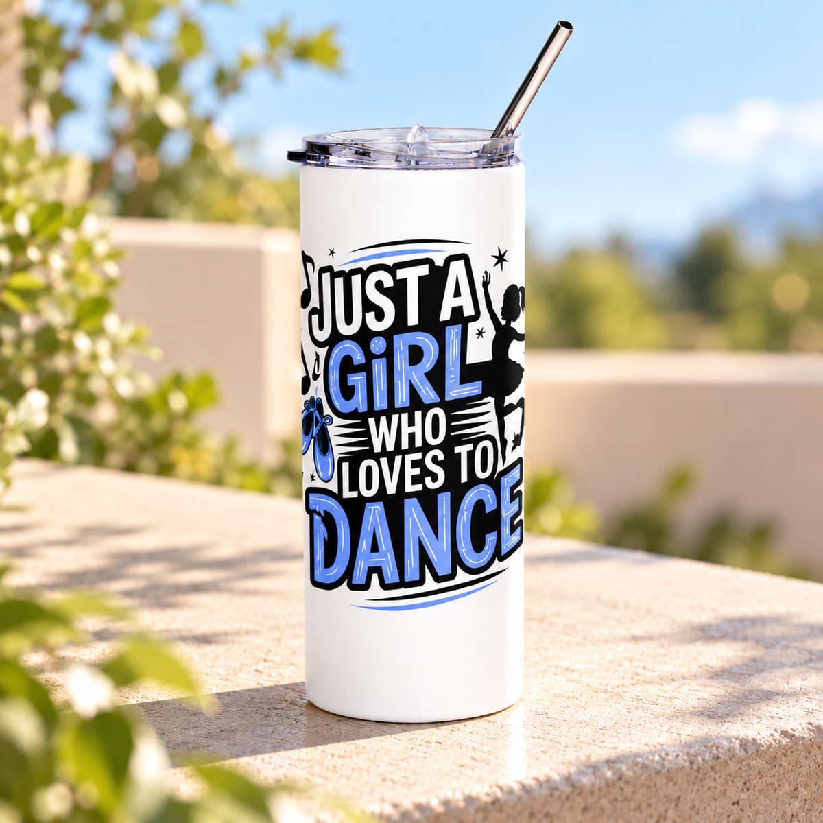 A white stainless steel skinny tumbler with a clear lid and metal straw, printed with "Just a Girl who Loves to Dance" in black and blue lettering with a ballerina silhouette, ballet slippers and music notes.