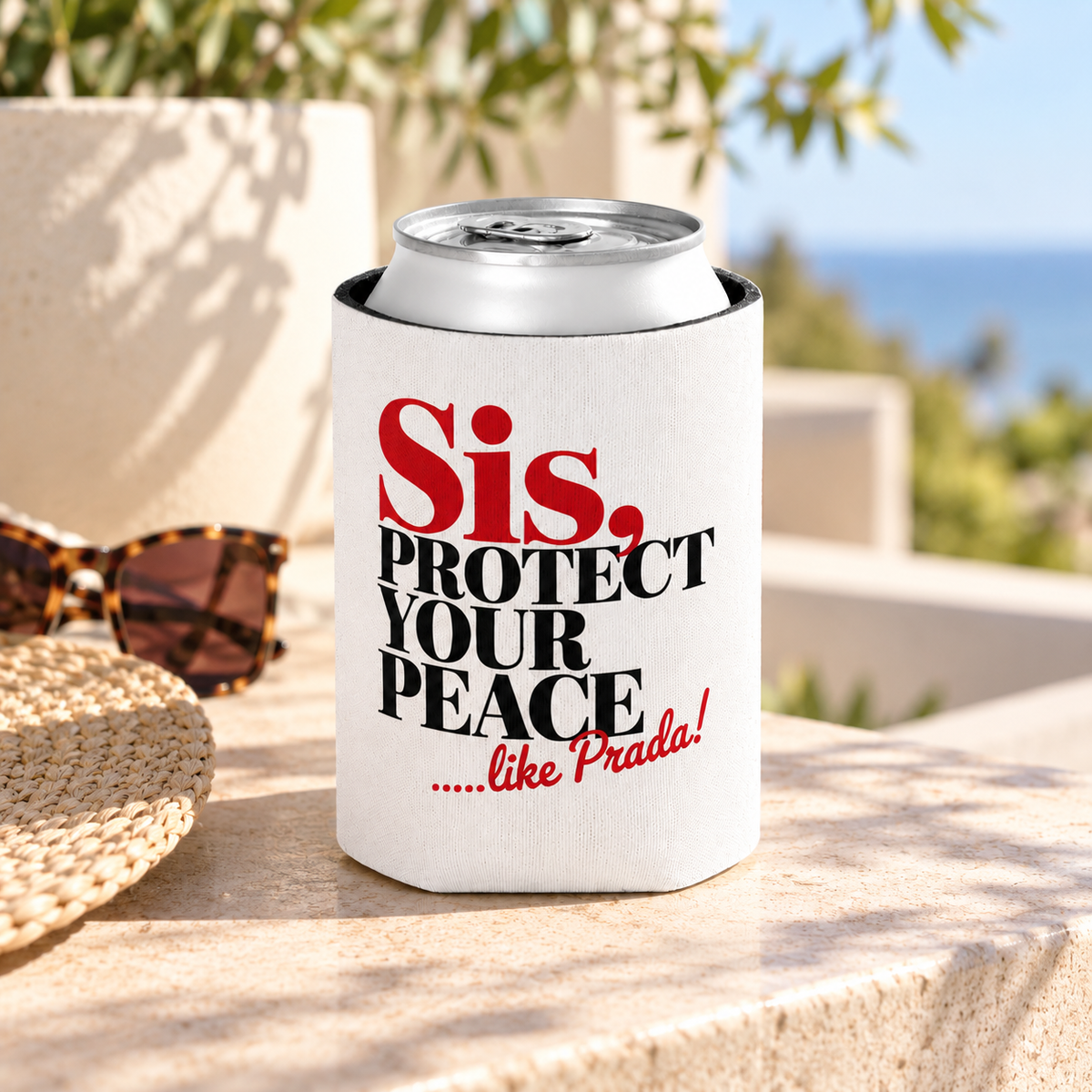 A white can cooler on a drink can, printed with "Sis, PROTECT YOUR PEACE" in bold red and black serif lettering with a short red script tagline.