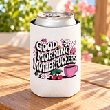 A white can cooler on a drink can, printed with "GOOD MORNING" and a cheeky adult slogan in retro bubble lettering with daisies, cherries, sparkles and a pink coffee cup.