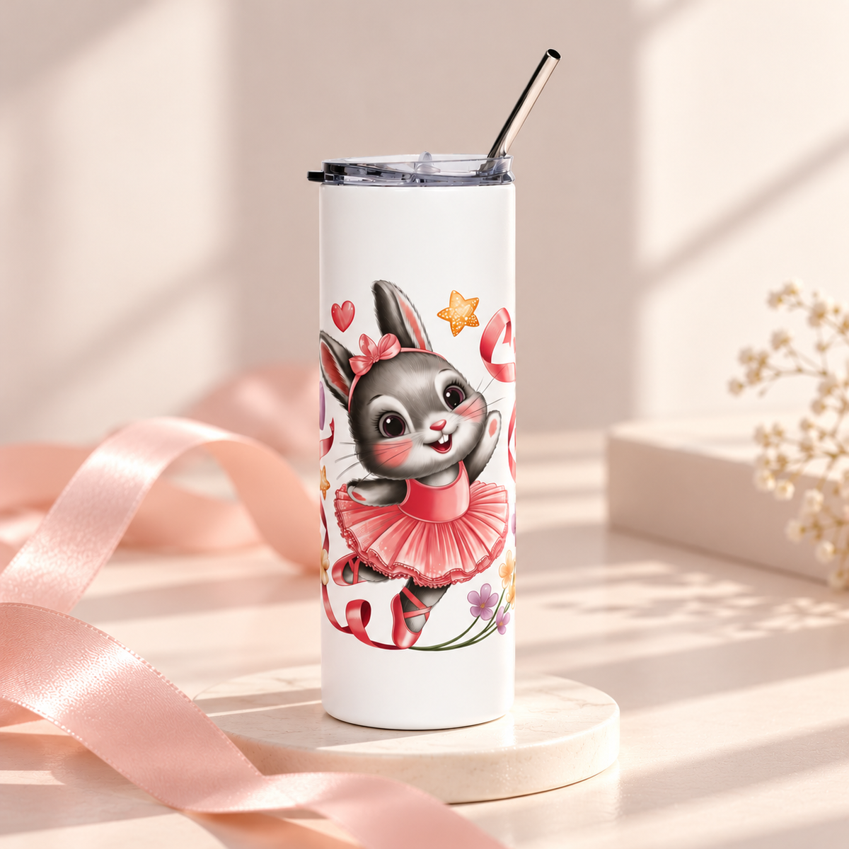 A white stainless steel skinny tumbler with a clear lid and metal straw, printed with a cute gray bunny ballerina in a pink tutu and hair bow, dancing among pink ribbons, hearts, stars and small flowers.
