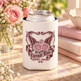 A white can cooler on a drink can, printed with pink roses in front of dark burgundy wings, framed by ornate vintage scrollwork, above a banner reading "Eternal Love".